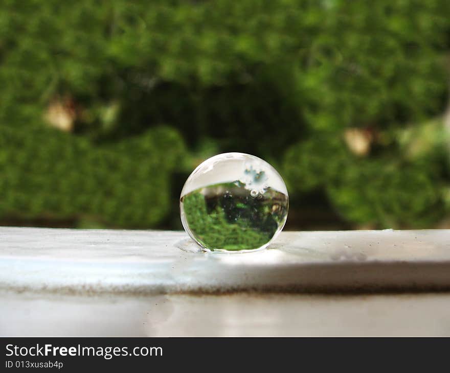 A single rain drop, on the window panel, with the background reflection. A single rain drop, on the window panel, with the background reflection