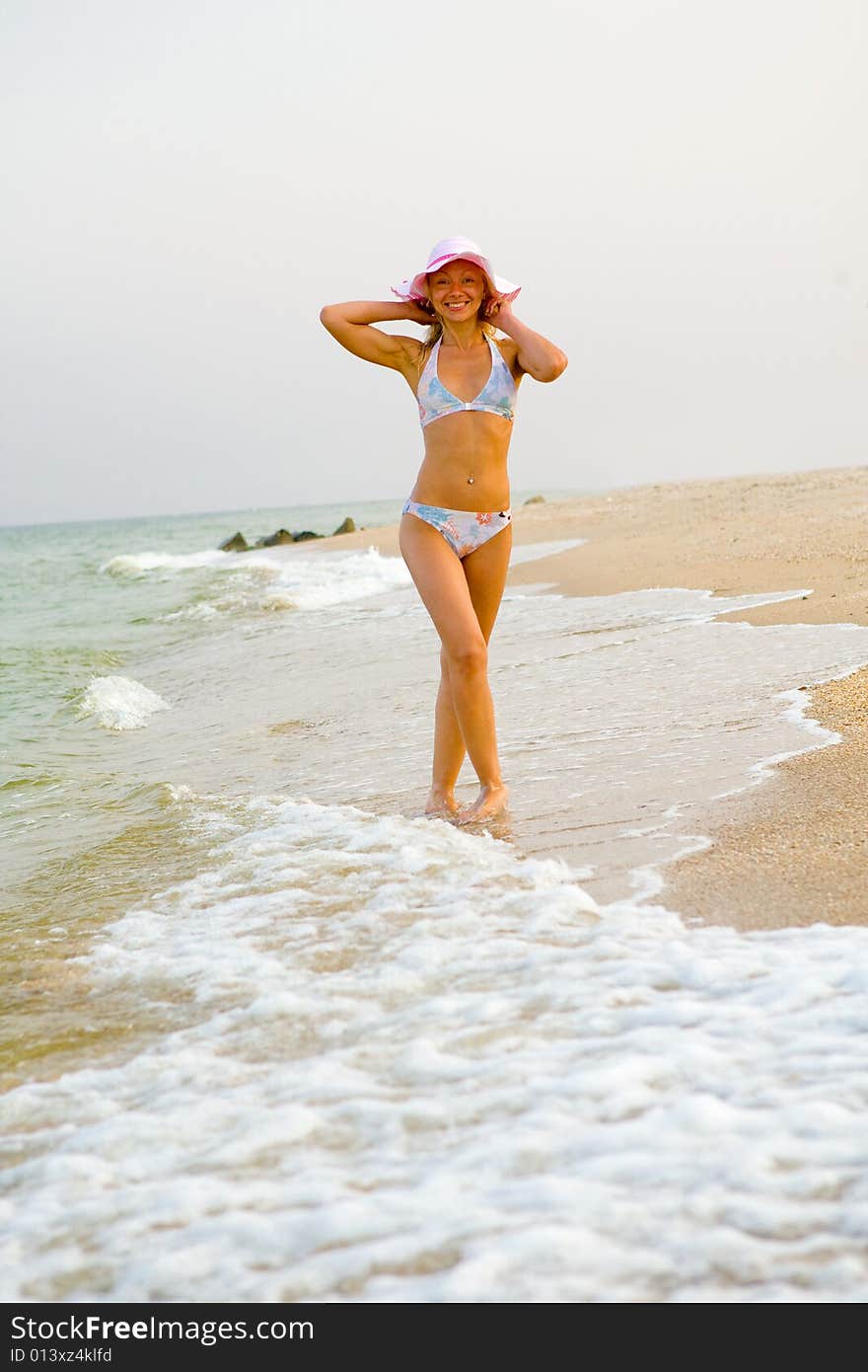 Beautiful young woman walking along sea shore