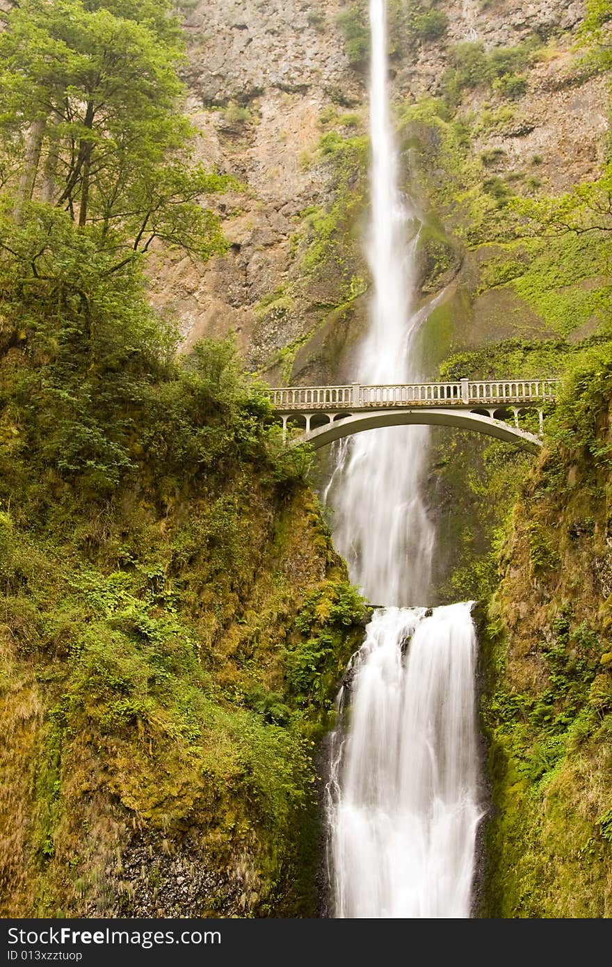 Multi layered waterfall in the mountains with arched bridge and trees. Multi layered waterfall in the mountains with arched bridge and trees