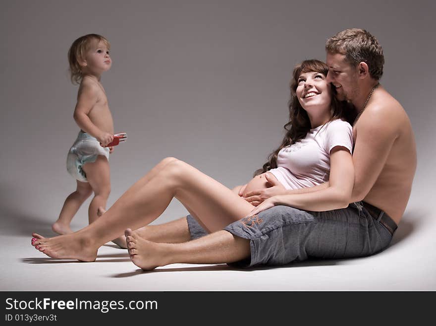 Mother, father and small daughter are seating on the floor. Mother, father and small daughter are seating on the floor