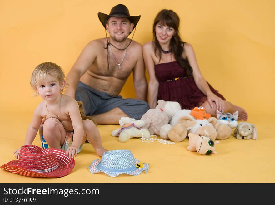 Pregnant mother, father, daughter with the hats and the toys in the studio. Pregnant mother, father, daughter with the hats and the toys in the studio