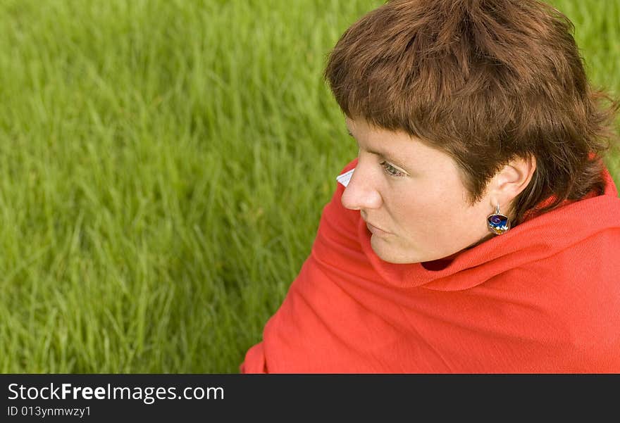 Closeup portrait of pretty redhead woman sitting on the grass