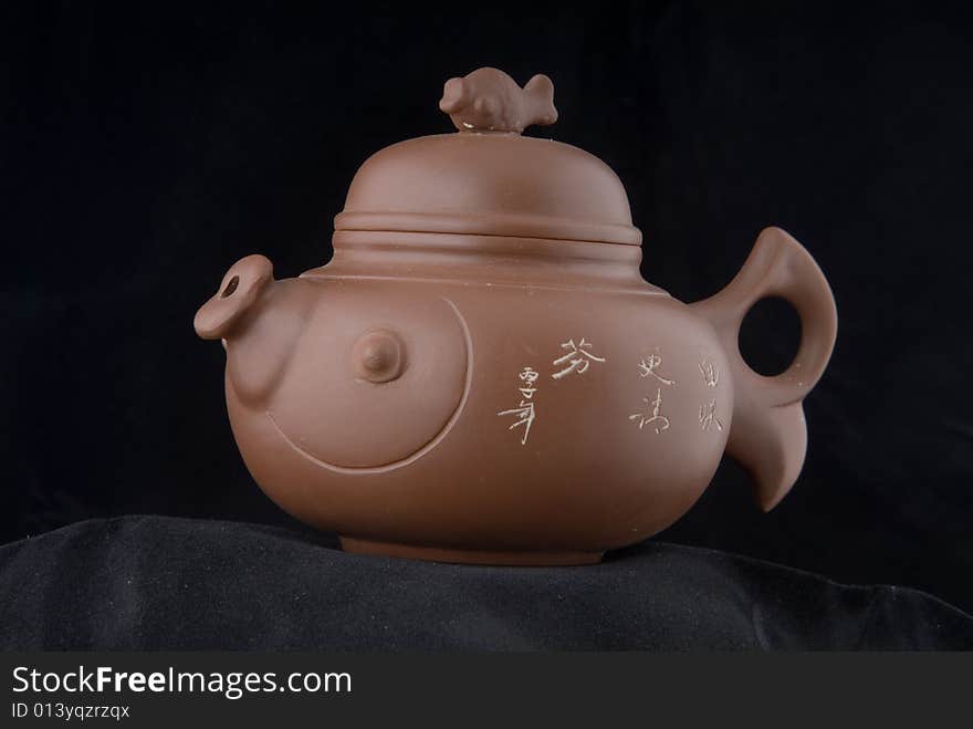 The fictile teapot is in dark background. The fictile teapot is in dark background.