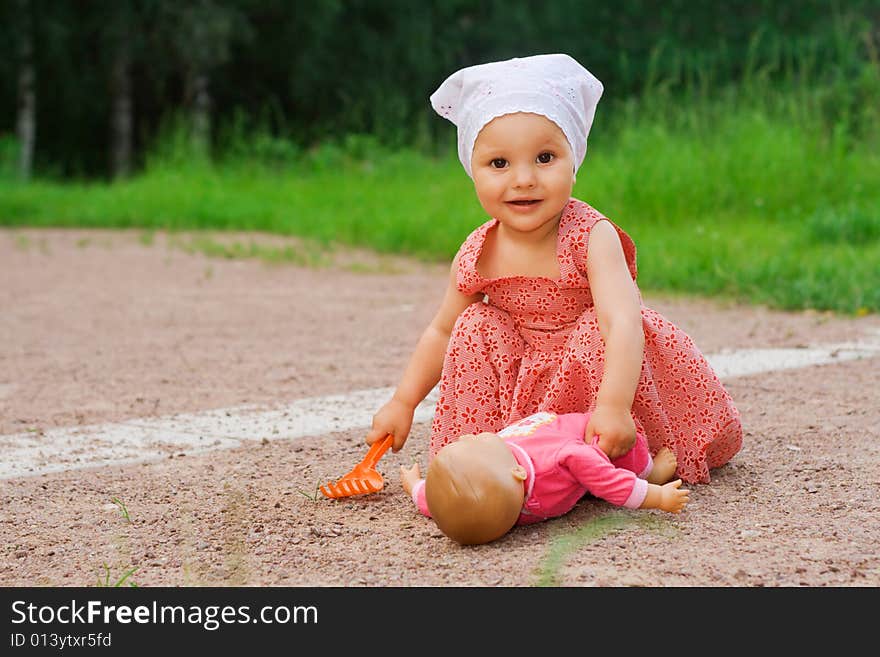 Small pretty girl playing with a doll in the park. Small pretty girl playing with a doll in the park