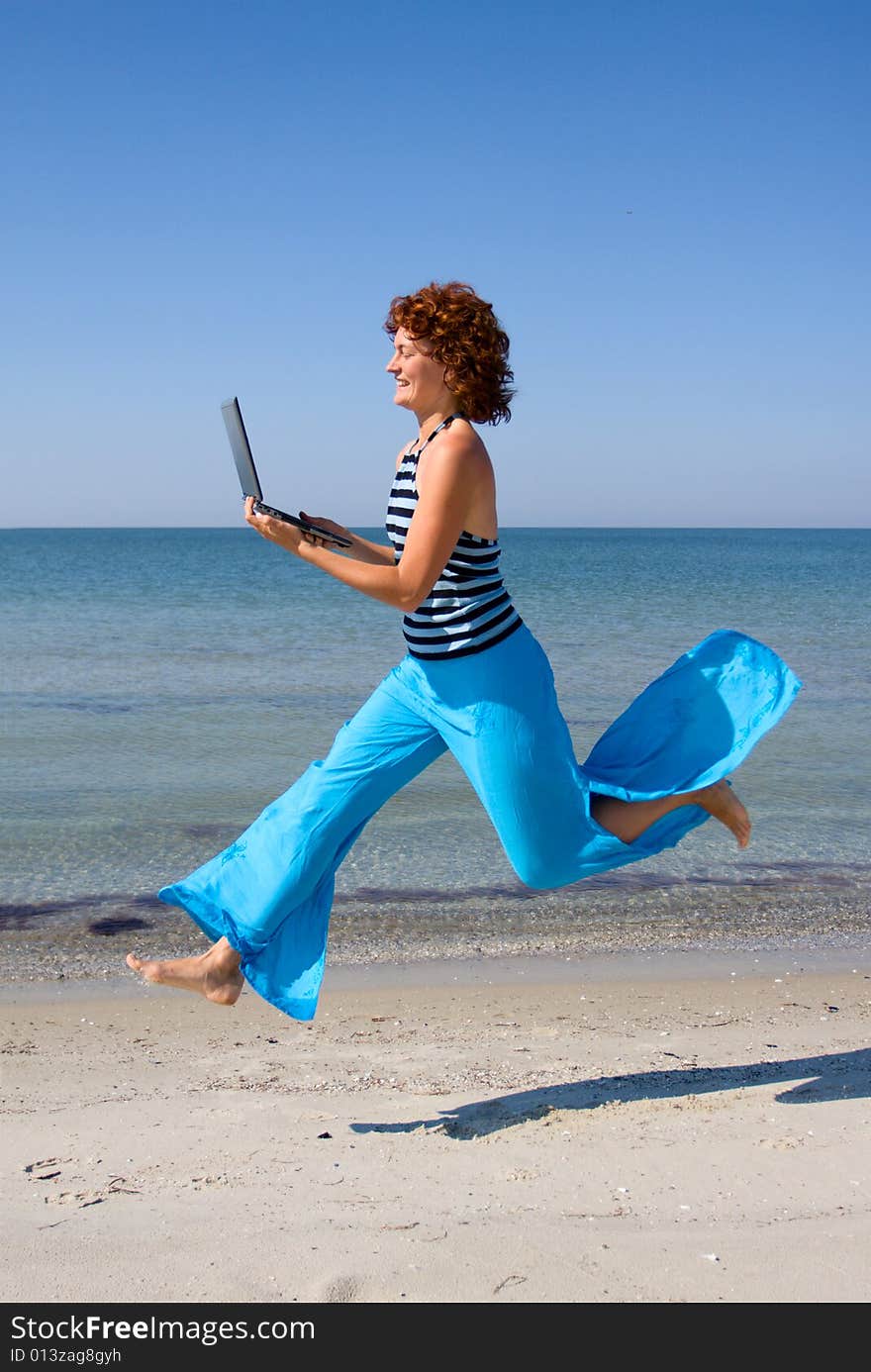 Girl with laptop running along sea coast. Girl with laptop running along sea coast