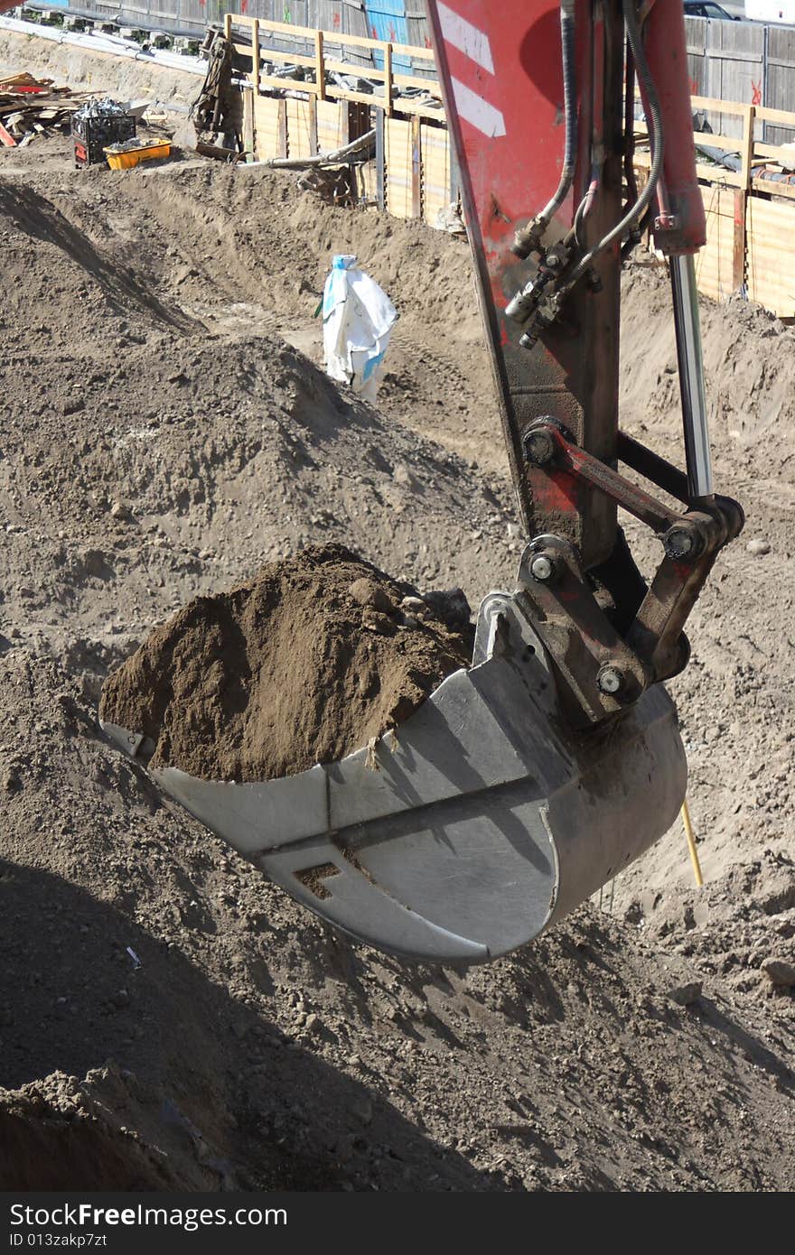 Excavator bucket on construction site digging up dirt