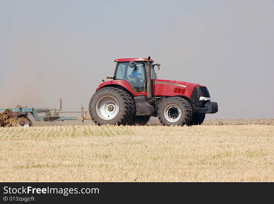 Large tractor pulling plow, throwing dust up in the air. Ukraine