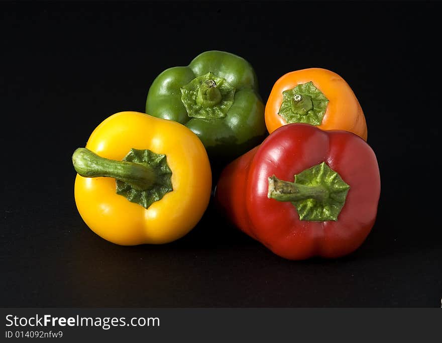 Close up of Red Yellow Orange and Green Peppers on a dark background