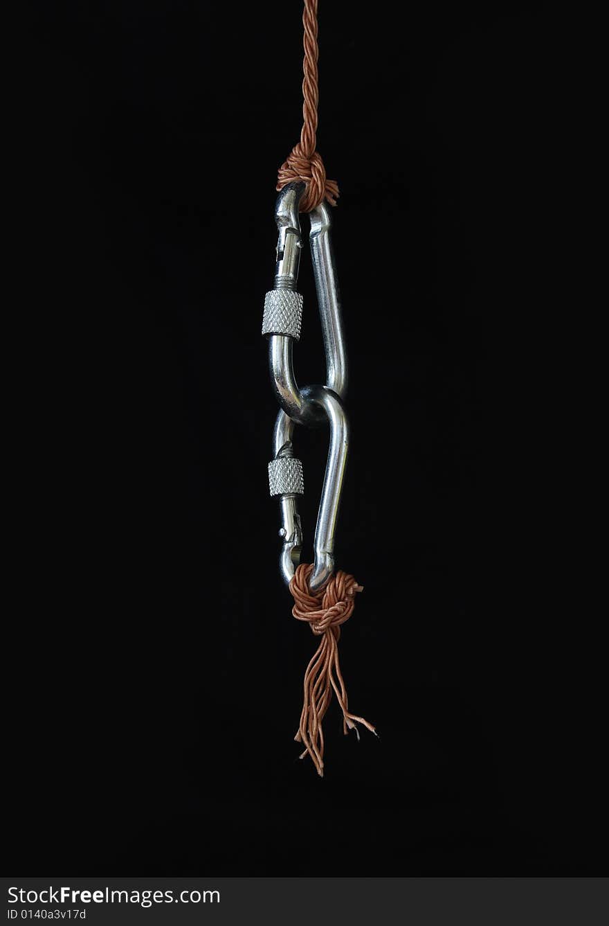 Two fastened clasps hanging with rope on black background