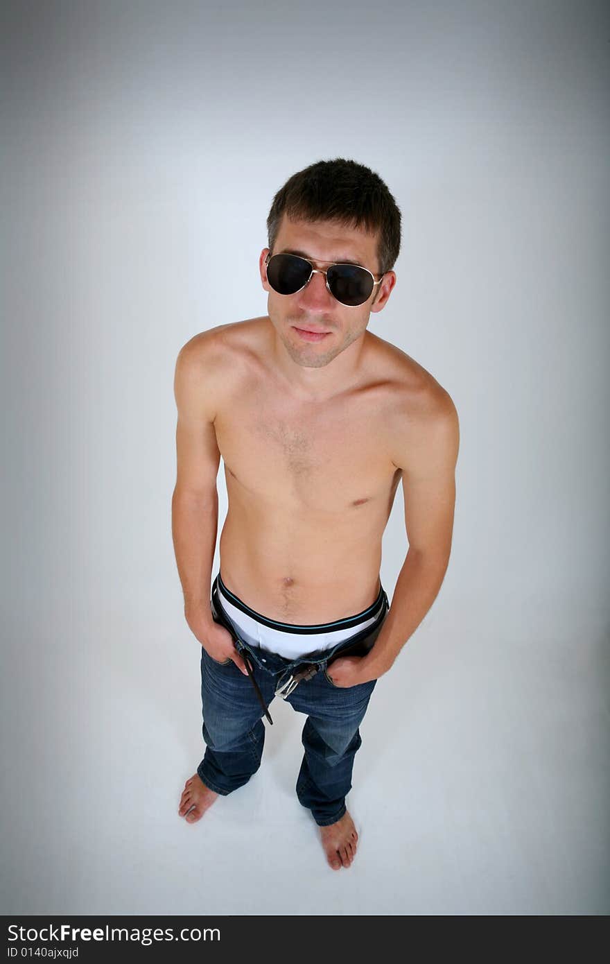 Topless young guy in jeans and glasses on grey background. Topless young guy in jeans and glasses on grey background