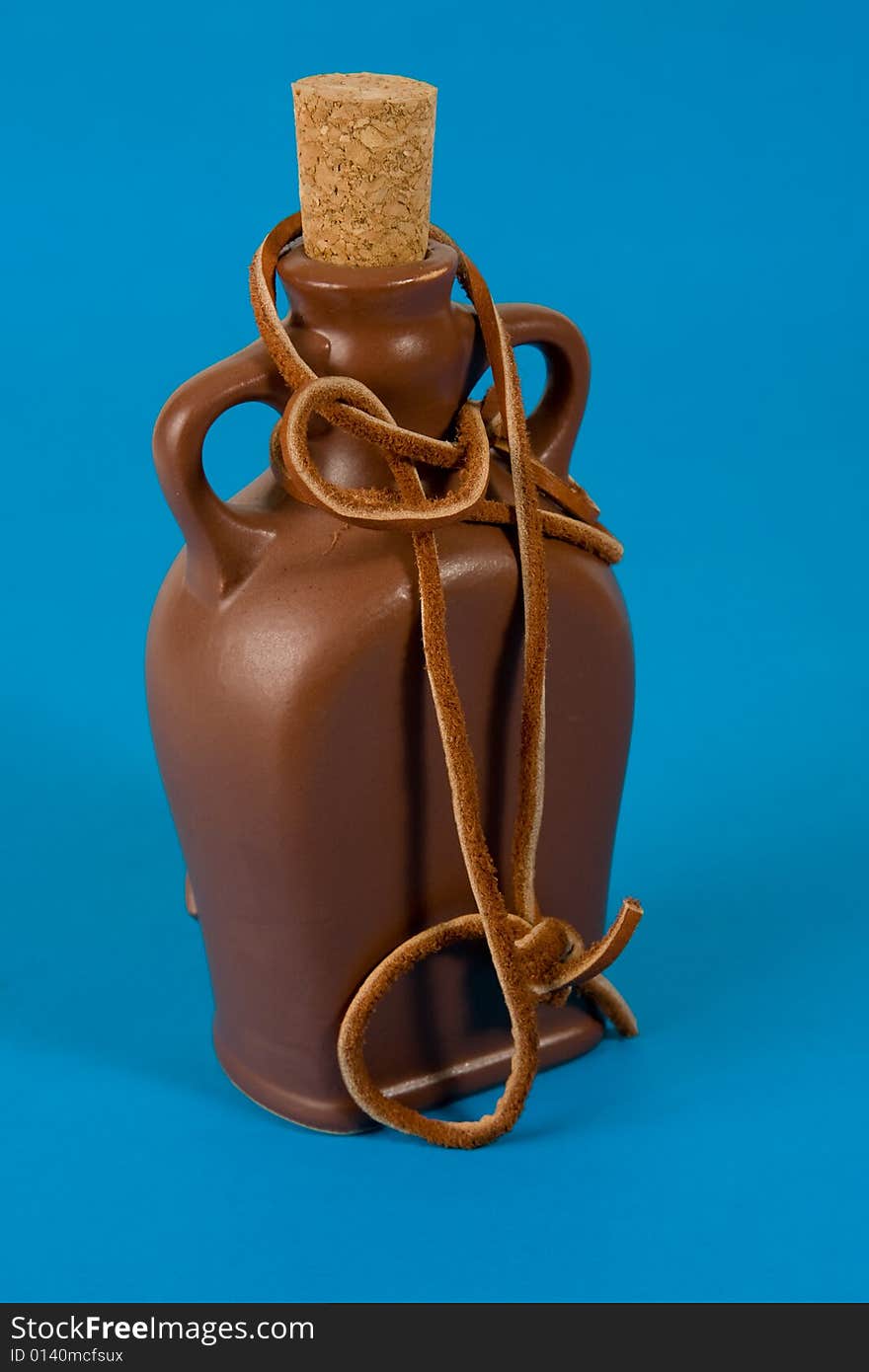 Pottery bottle with a cork on blue background