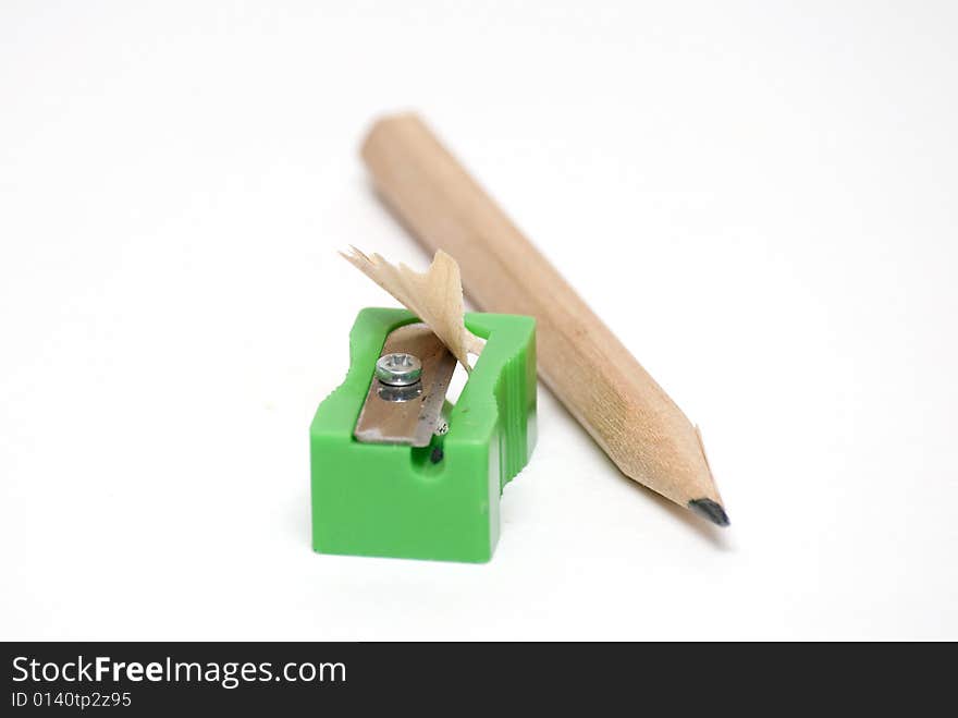 Wooden pencil besides a green plastic sharpener. Wooden pencil besides a green plastic sharpener