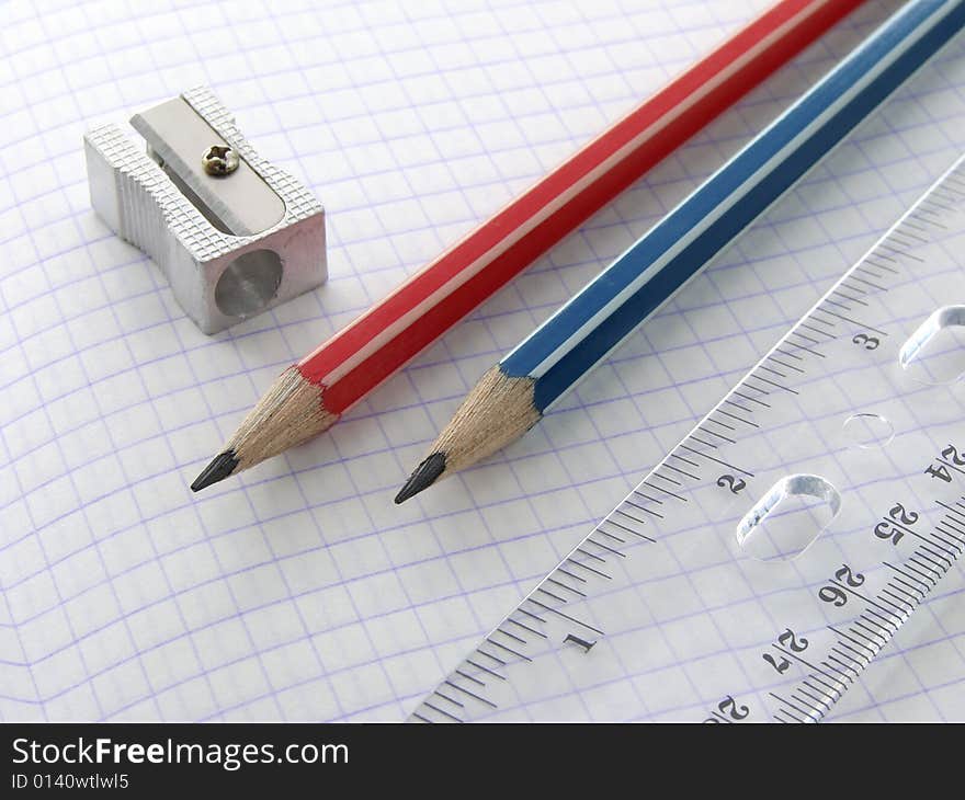 Two pencils and a ruler with sharpener on the workbook page. Two pencils and a ruler with sharpener on the workbook page