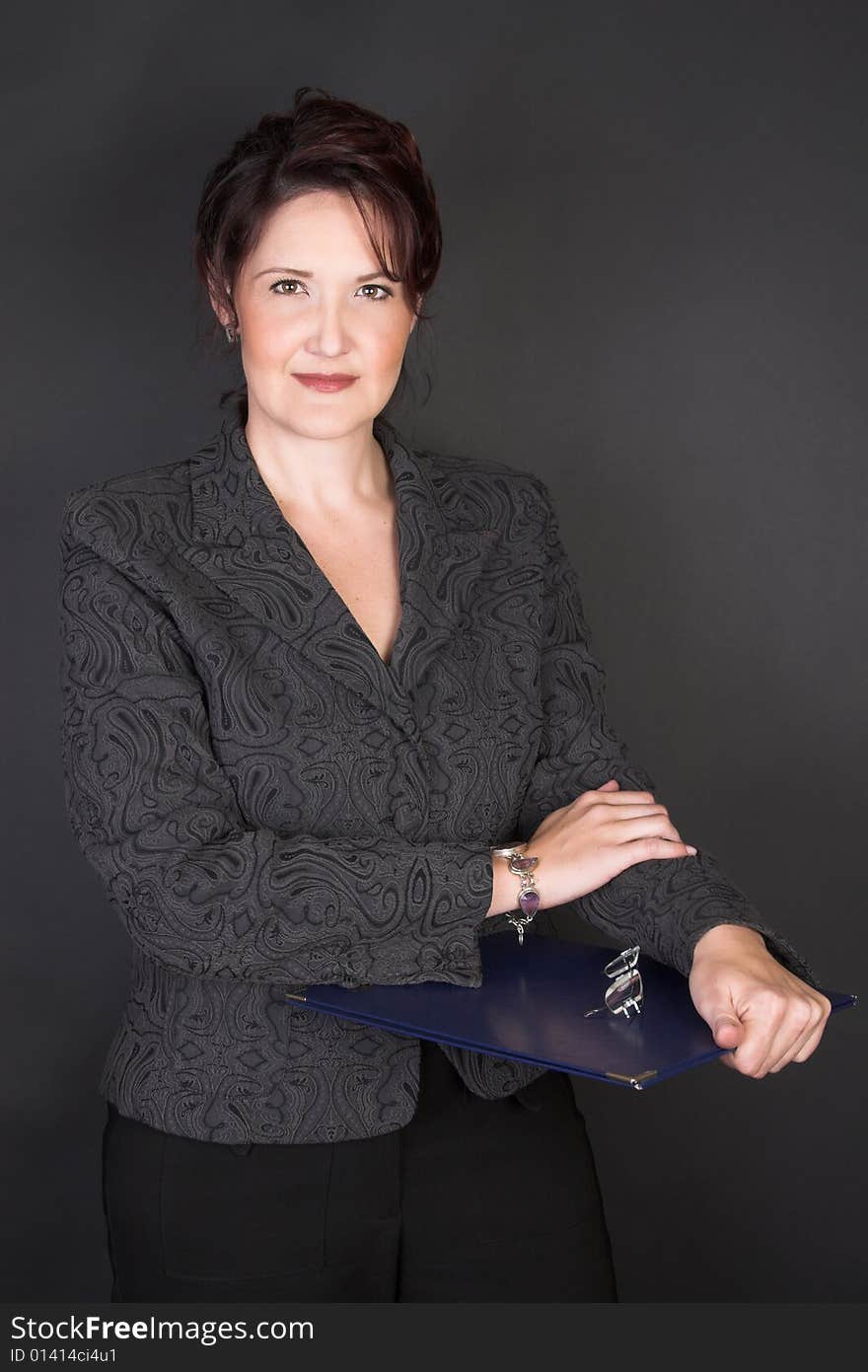 Composed Businesswoman holding a blue file against a black background. Composed Businesswoman holding a blue file against a black background