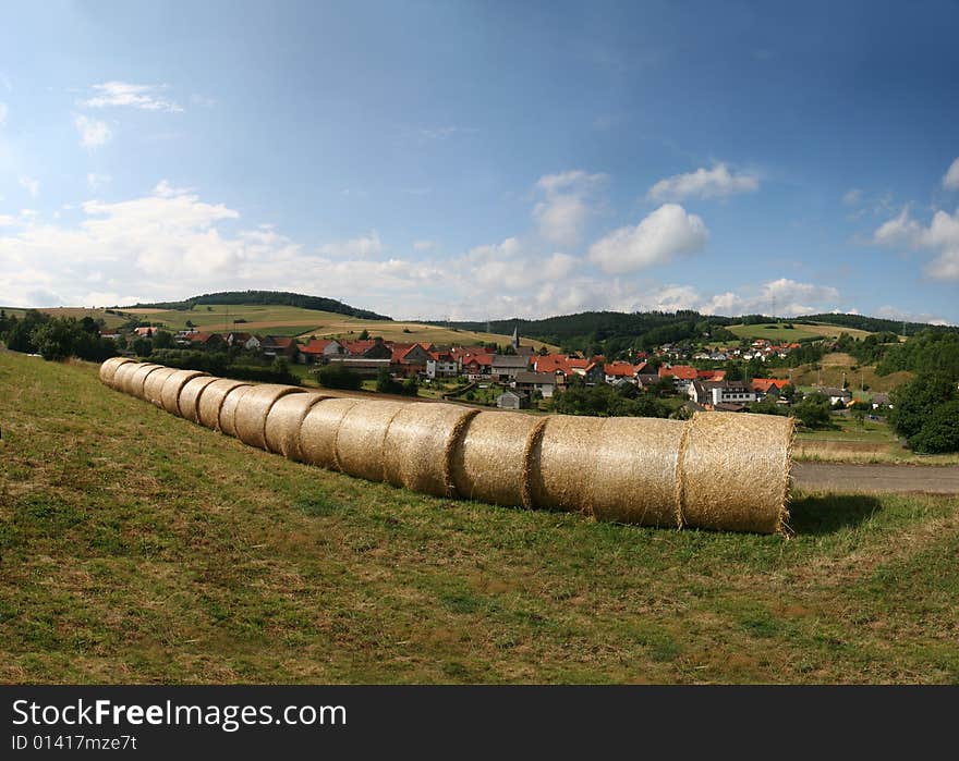 Haybales in a german landscape in the north of Hesse. In the background the village of Mühlbach (Neuenstein) in the Knüll mountains.Hay bales on an idyllic field near Kassel and Ahnatal-Weimar in Germany