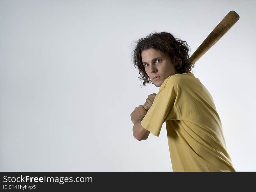 An young man holding a bat.  He is looking at the camera, and has a serious expression on his face.  Horizontally framed shot. An young man holding a bat.  He is looking at the camera, and has a serious expression on his face.  Horizontally framed shot.