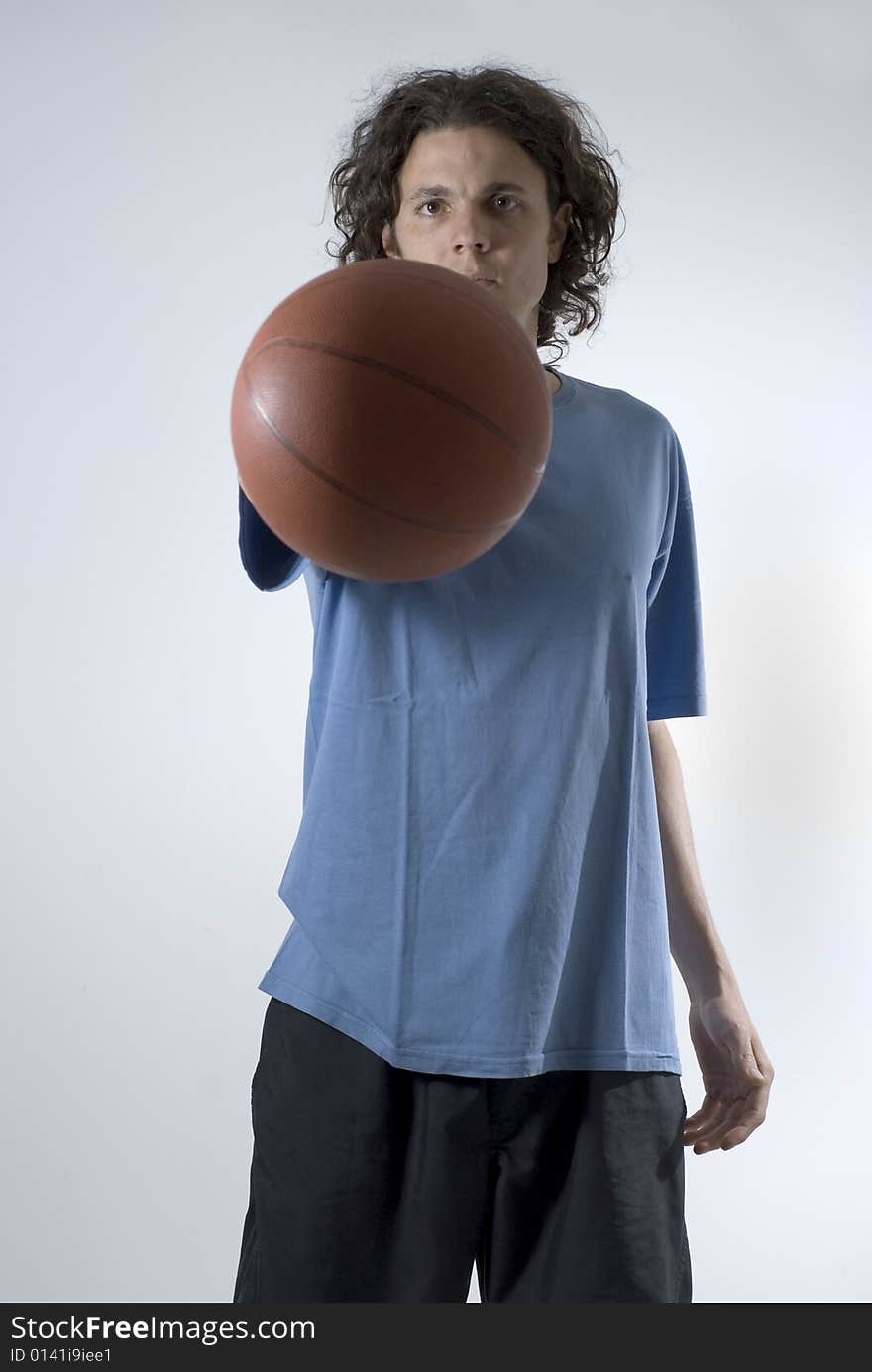 An athlete holding a basket ball with a straight arm.  He is looking at the camera.  He has a serious expression on his face. Vertically framed shot. An athlete holding a basket ball with a straight arm.  He is looking at the camera.  He has a serious expression on his face. Vertically framed shot.