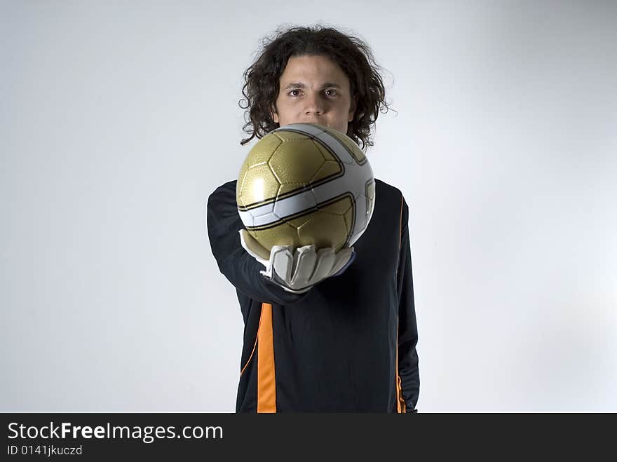 An athlete holding a soccer ball with a straight arm.  He is looking at the camera.  He has a serious expression on his face. Horizontally framed shot. An athlete holding a soccer ball with a straight arm.  He is looking at the camera.  He has a serious expression on his face. Horizontally framed shot.