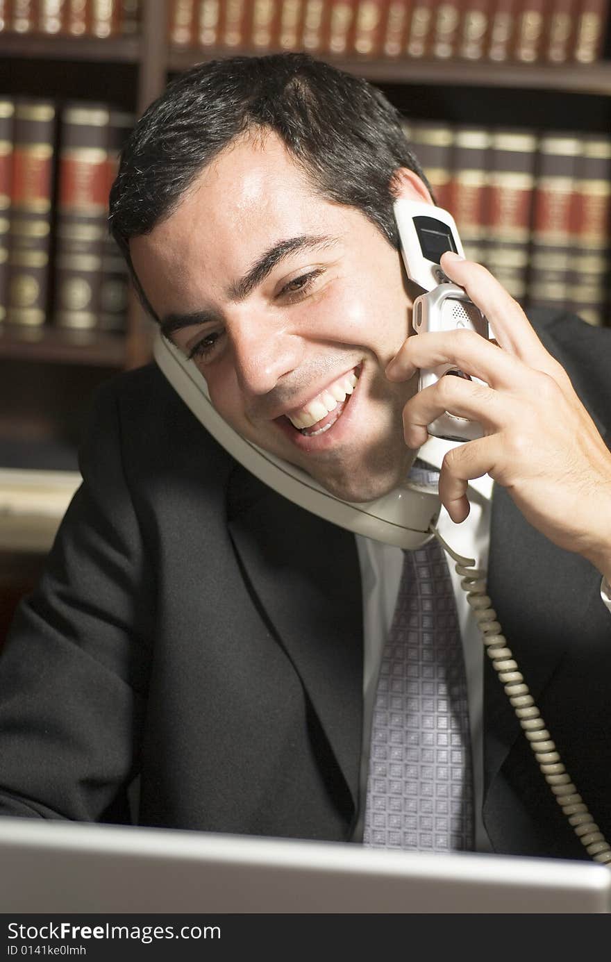 Happy businessman on phone in office. Vertically framed photo.