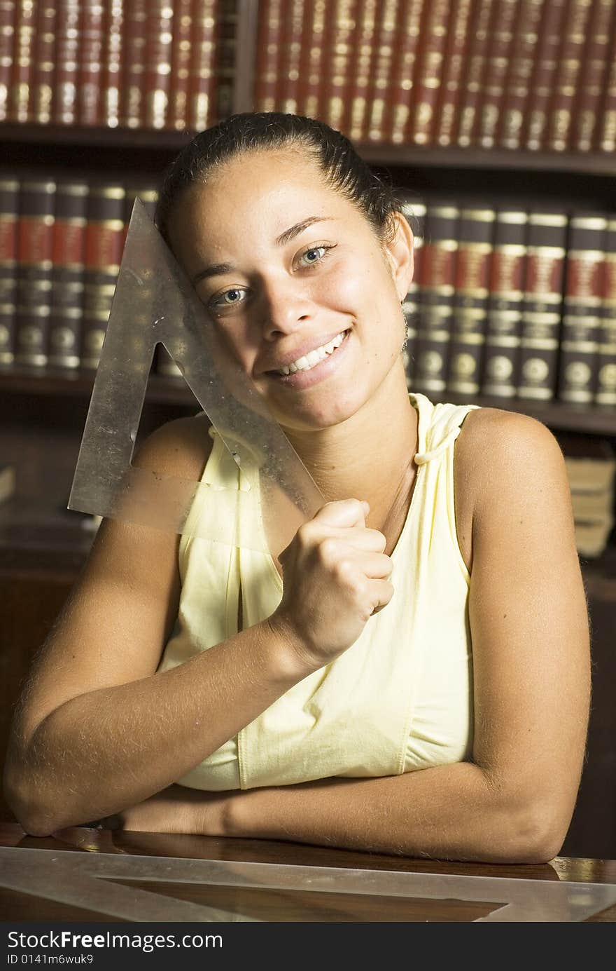 Smiling girl holding a drafting tool in an office full of books. Vertically framed photo. Smiling girl holding a drafting tool in an office full of books. Vertically framed photo.