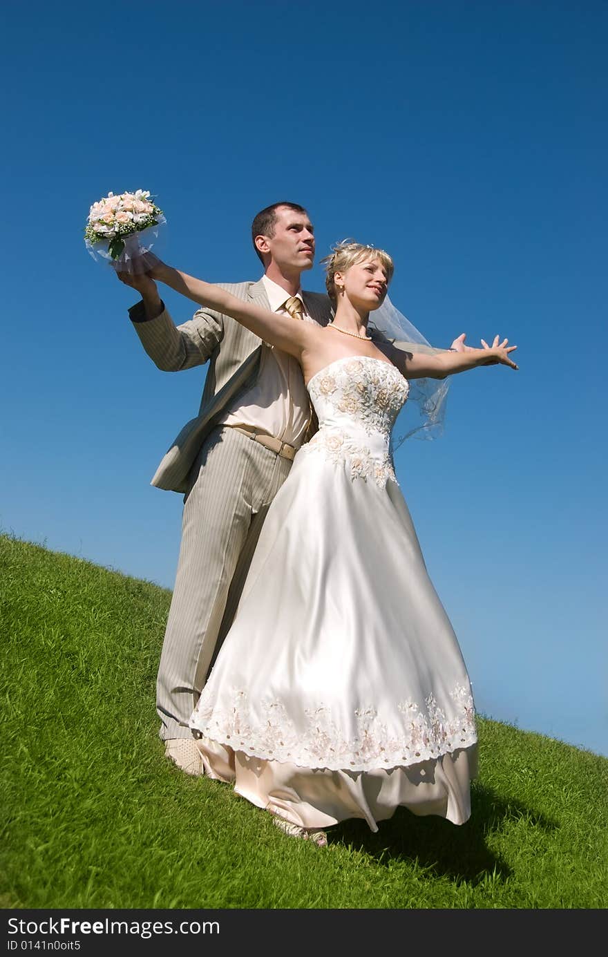 Bride and groom on the hill against blue sky