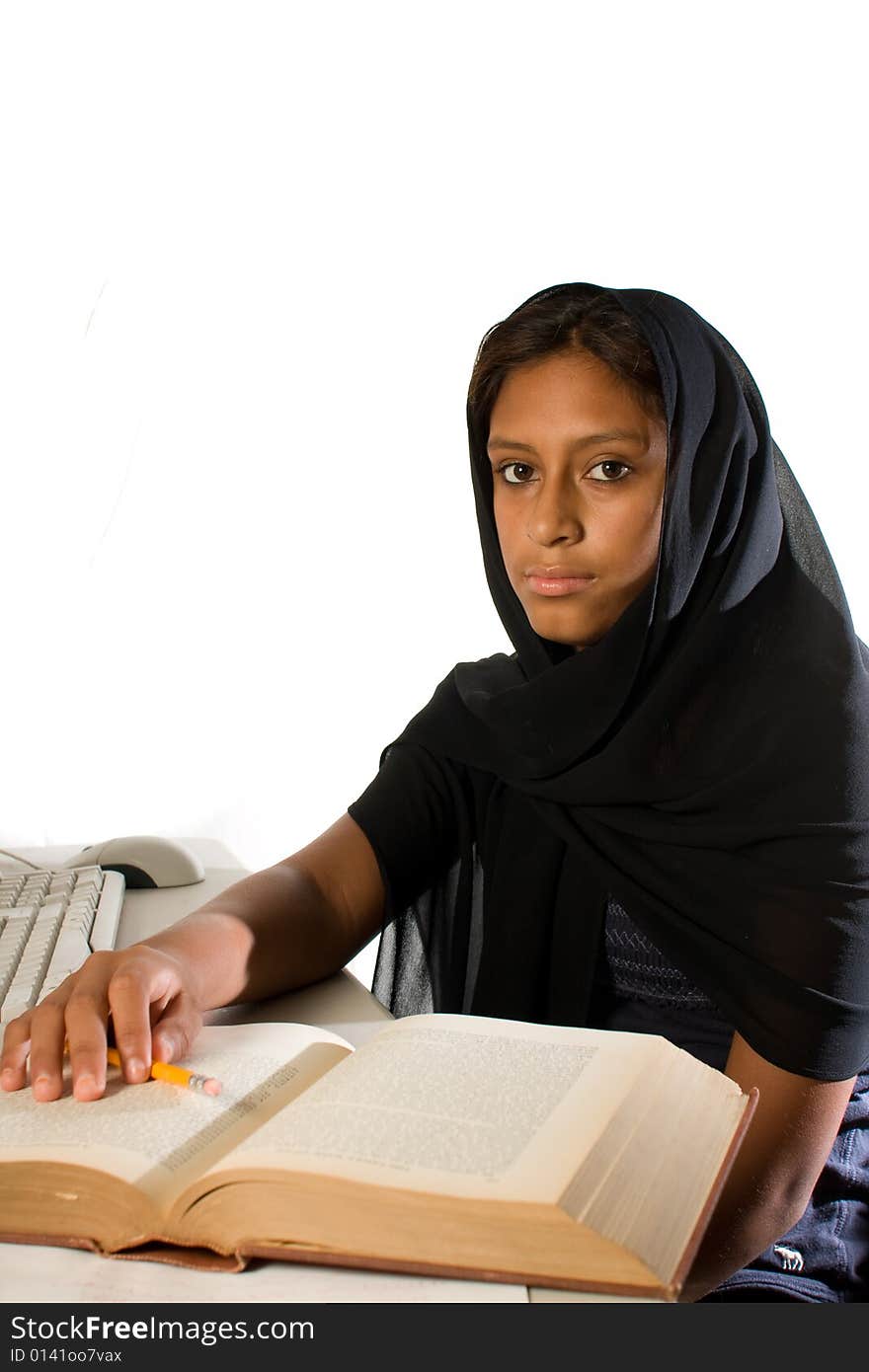 A young Muslim woman wearing a black head scarf looking at the camera. Studying with a computer and a book. A young Muslim woman wearing a black head scarf looking at the camera. Studying with a computer and a book.