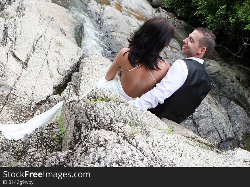 Happy bride and groom standing on top of a mountain.