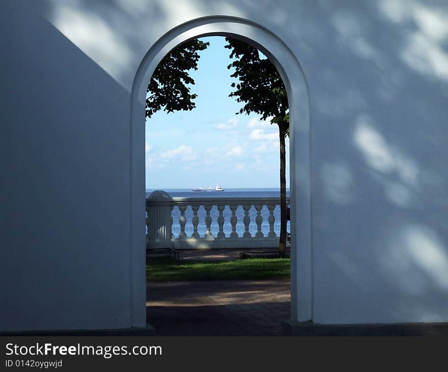 Arch in a white wall with a kind at the seaside