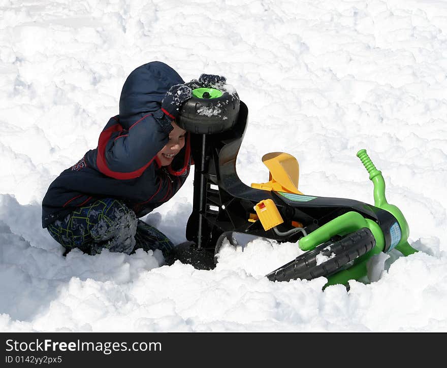 Young boy playing with a three wheeled toy in the snow. Young boy playing with a three wheeled toy in the snow