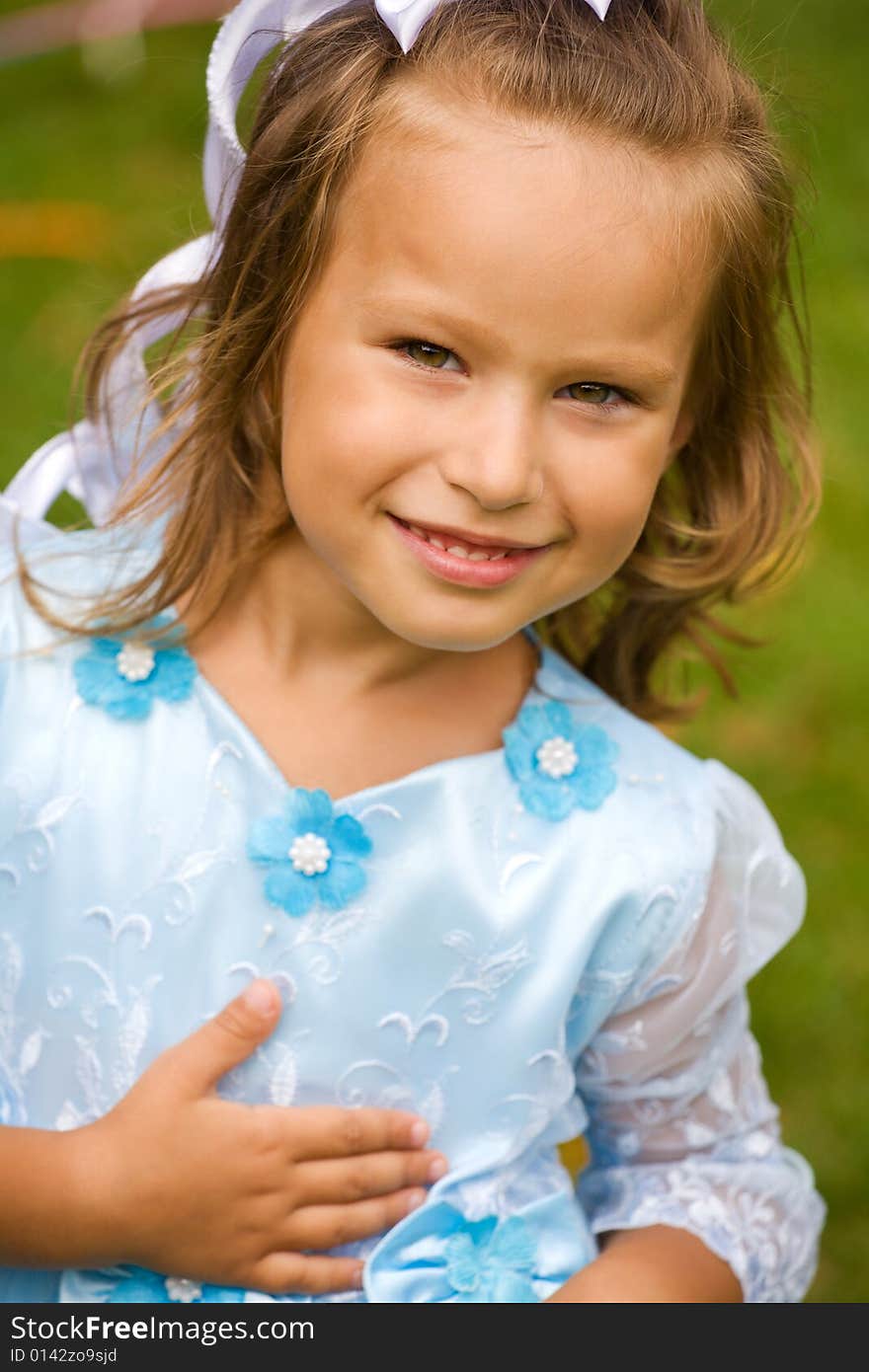 Portrait of little girl in blue dress on the green grass. Portrait of little girl in blue dress on the green grass