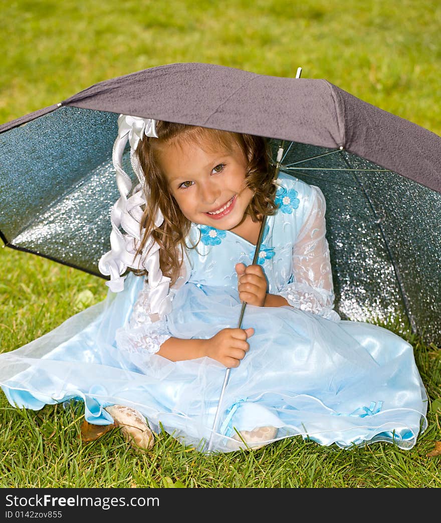 Portrait of little girl in blue dress on the green grass under umbrella. Portrait of little girl in blue dress on the green grass under umbrella