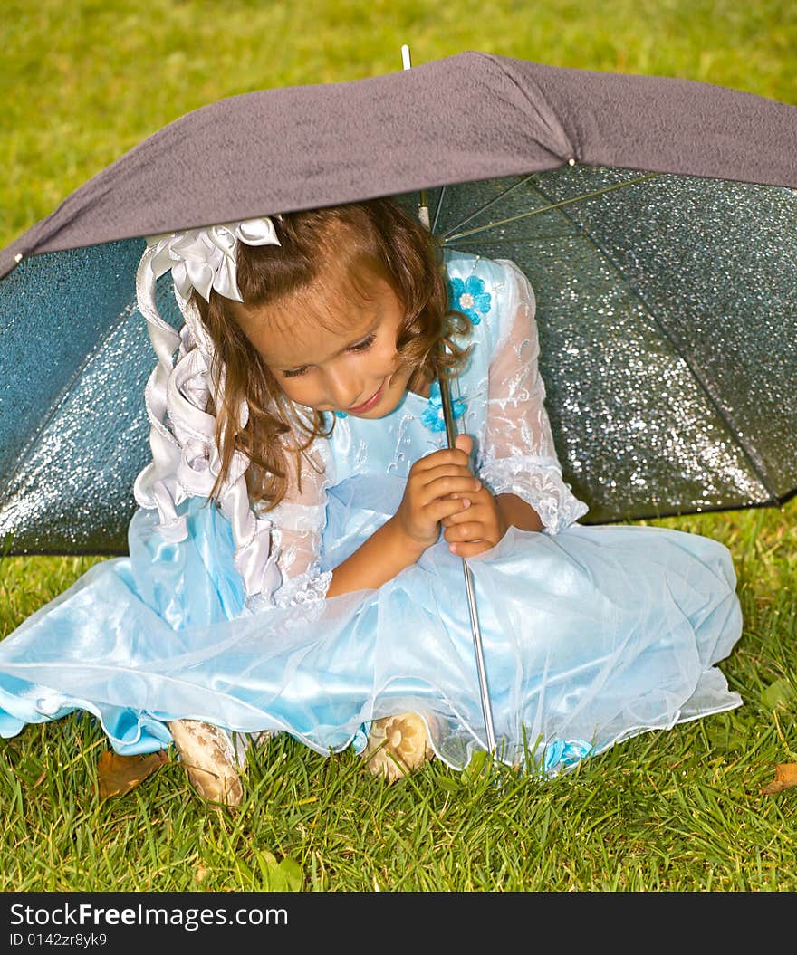 Closeup portrait of little girl sitting under umbrella on green grass. Closeup portrait of little girl sitting under umbrella on green grass