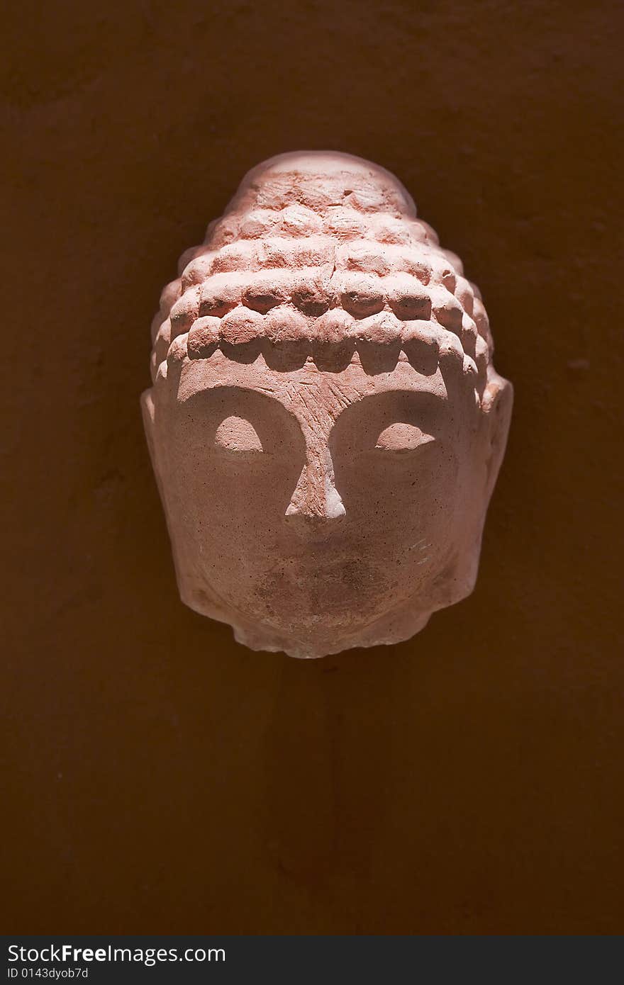 A red Buddha head made from stone