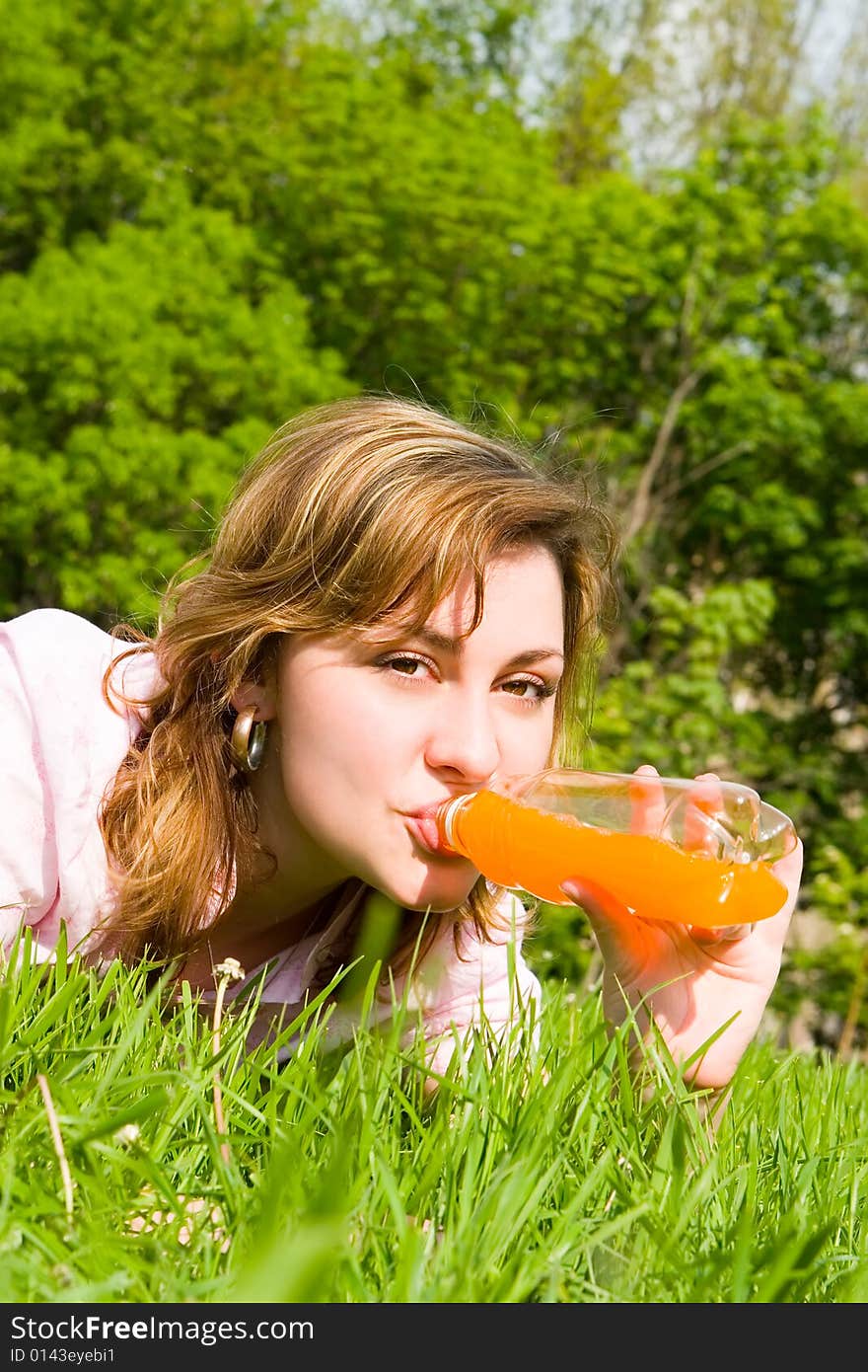 Pretty woman drinking juice on the summer glade