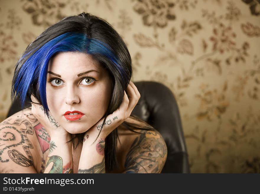 Pretty young woman with many tattoos in a leather chair. Pretty young woman with many tattoos in a leather chair