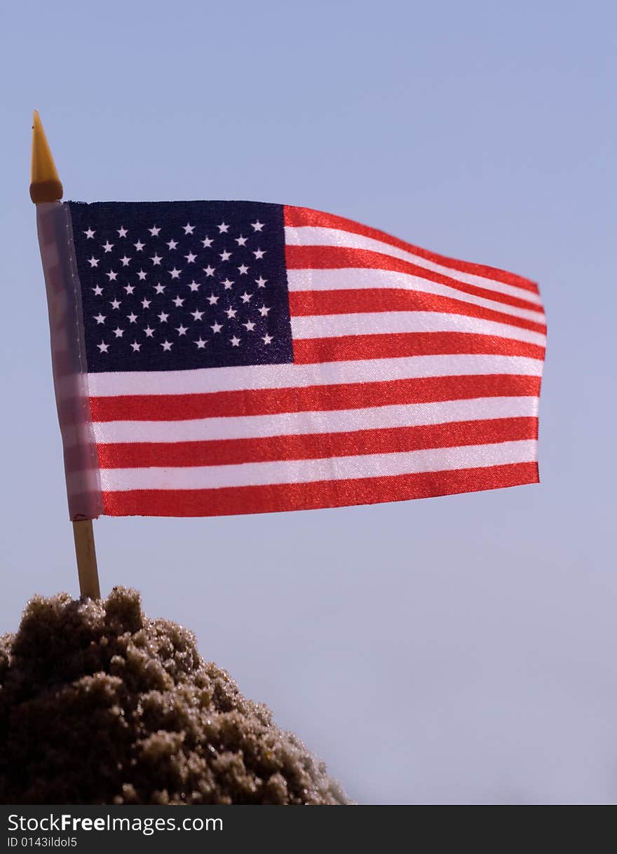 A united states of america flag in the sand on a sunny day. A united states of america flag in the sand on a sunny day.