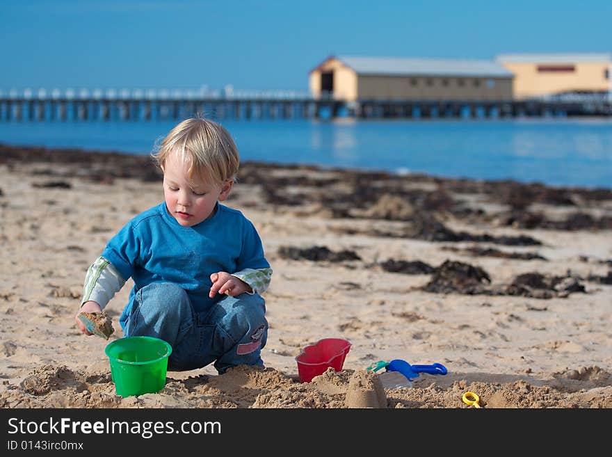 A young boy building sand castles on the beach. A young boy building sand castles on the beach.