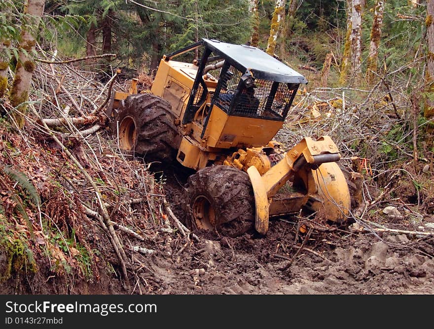 Skidder climbing muddy hill in order to retrieve logs. Skidder climbing muddy hill in order to retrieve logs.