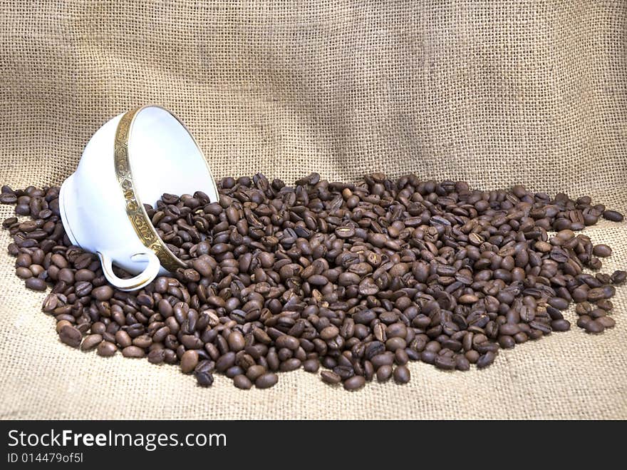 Coffee beans with a coffee cup, sack as background