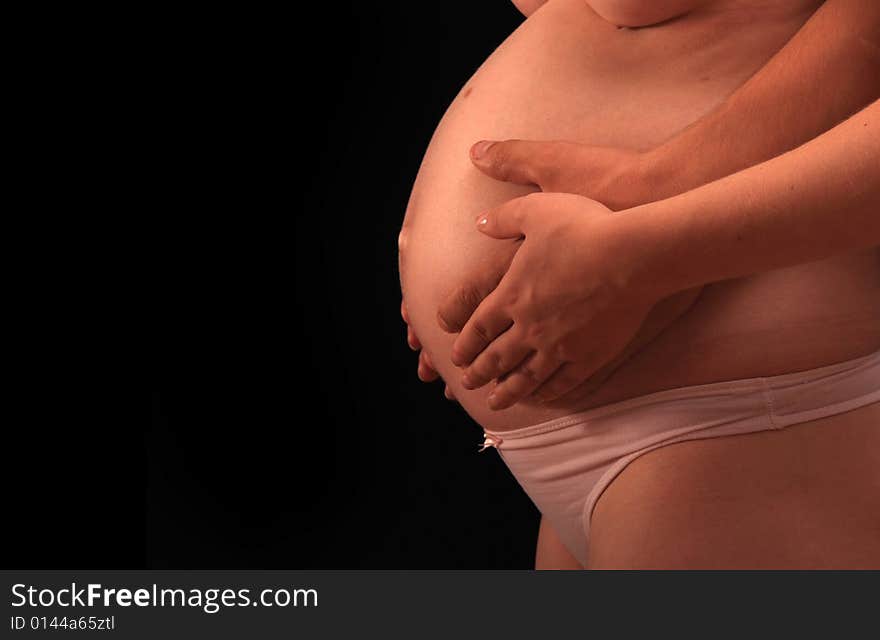 Hands hold a pregnant belly, side view. Hands hold a pregnant belly, side view