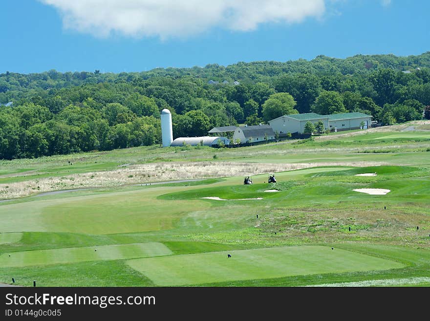 A Golf course with farm in the background