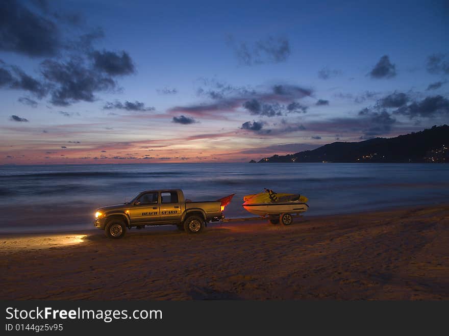 Beach guard patrolling sunset lit beach in Thailand