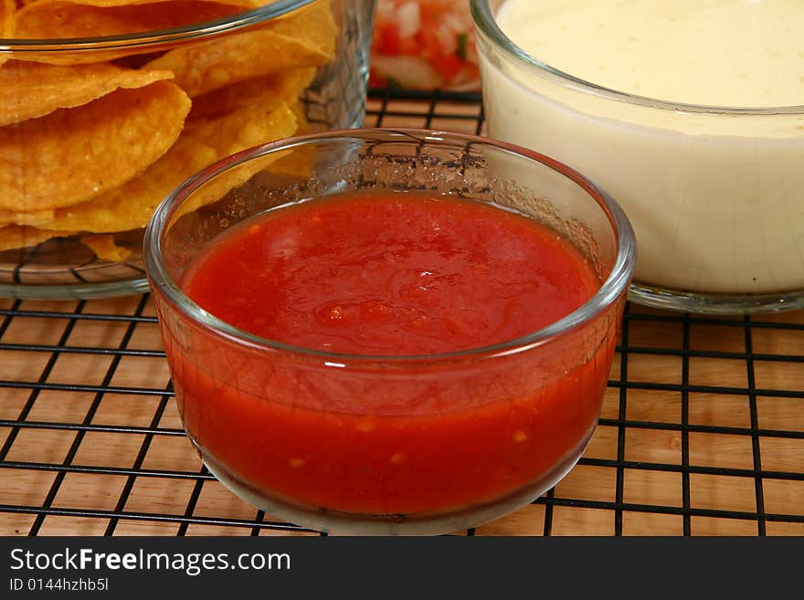 Glass bowls of salsa, cheese dip and tortilla chips in kitchen or restaurant. Glass bowls of salsa, cheese dip and tortilla chips in kitchen or restaurant.