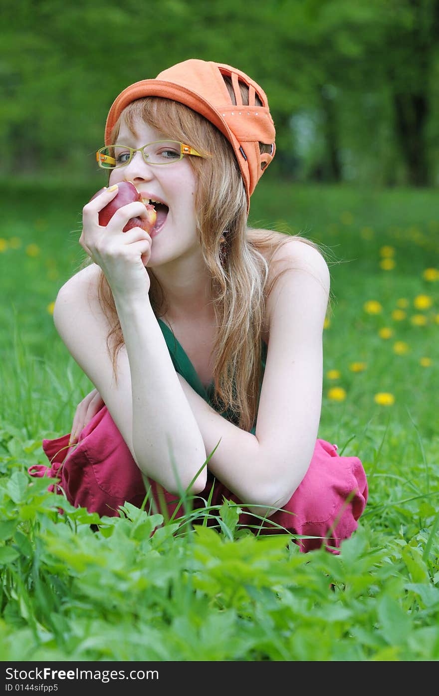 Happy young girl spectacled eats an apple. Happy young girl spectacled eats an apple