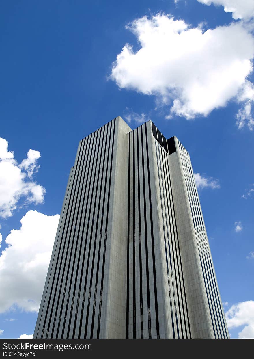 High modern skyscraper on a background of a blue sky and clouds. High modern skyscraper on a background of a blue sky and clouds.