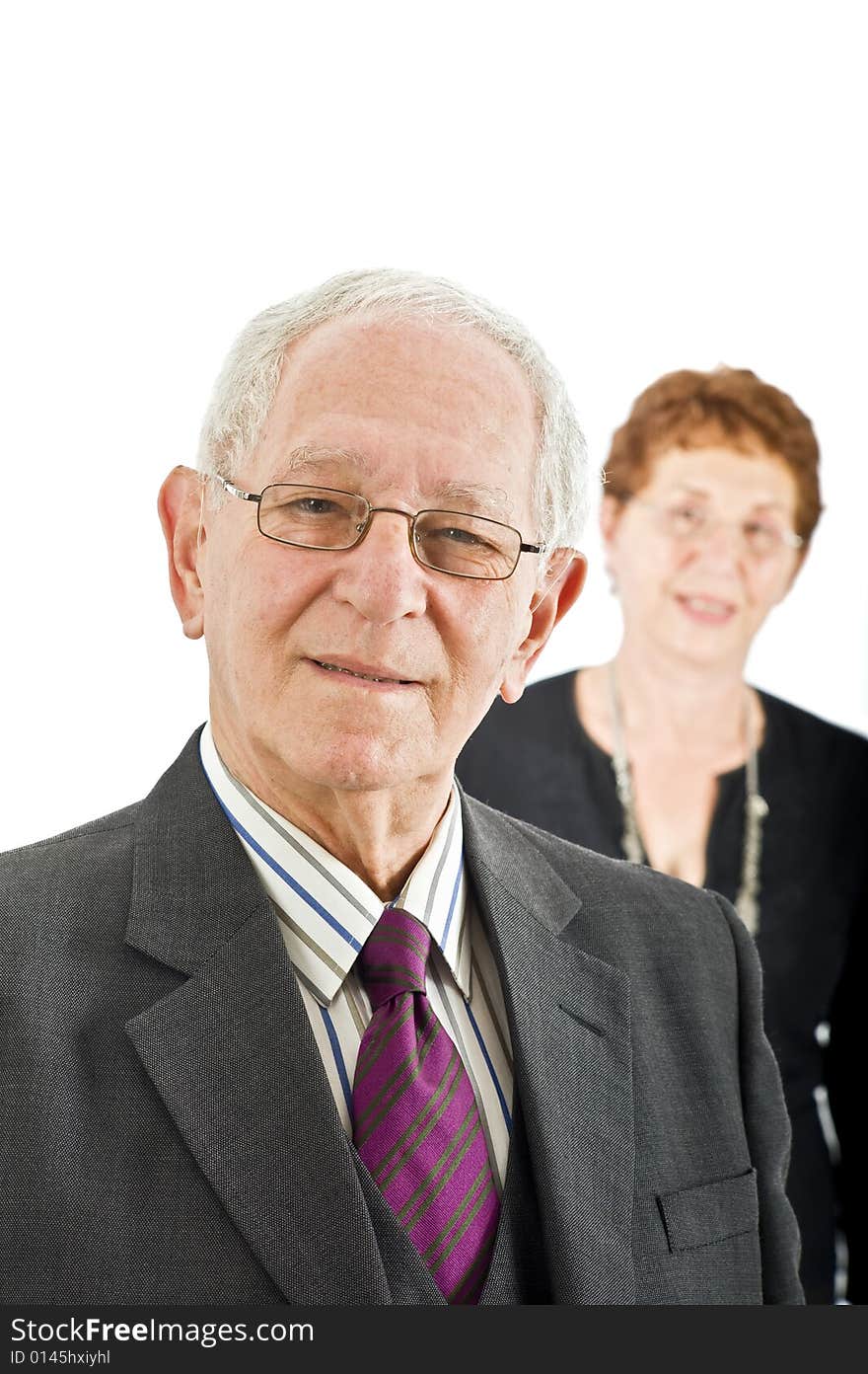 Closeup portrait off a senior businessman with colleague in the background isolated on white