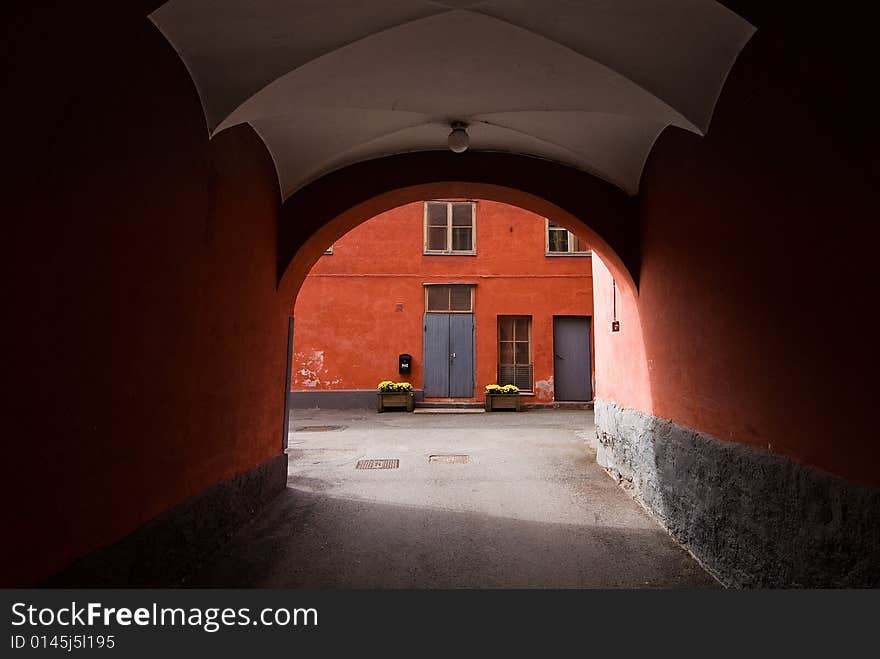 Red gate of historic colorful building with doors windows and yellow flowers