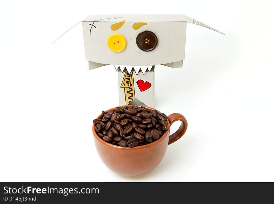 Cup with coffee beans and cardboard toy with insane expression. Cup with coffee beans and cardboard toy with insane expression