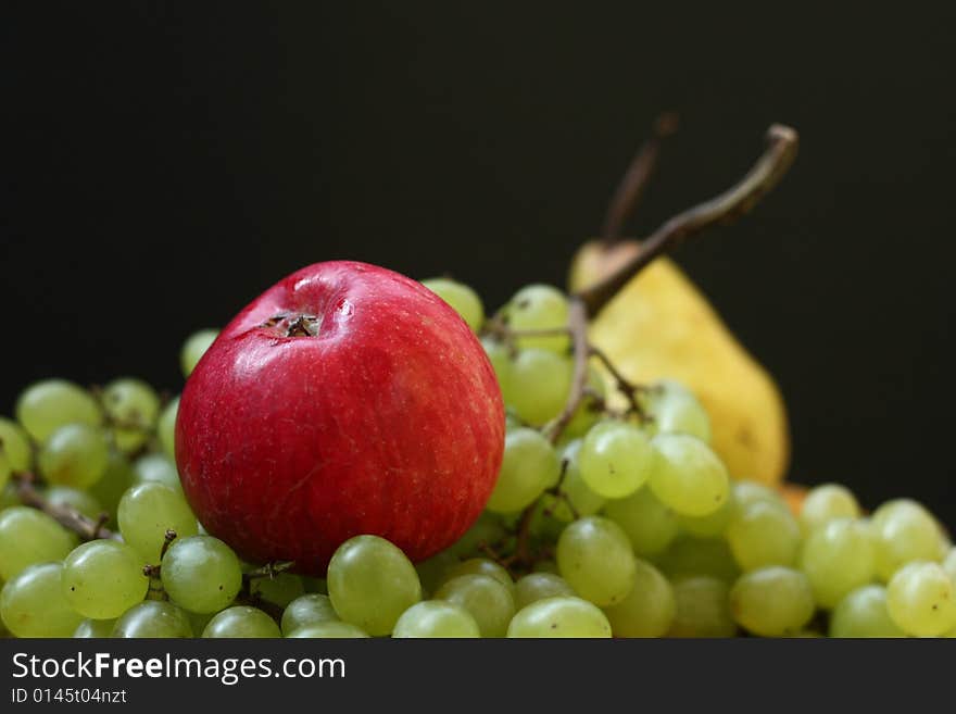 Red apple, green grape and yellow pear on black background. Red apple, green grape and yellow pear on black background