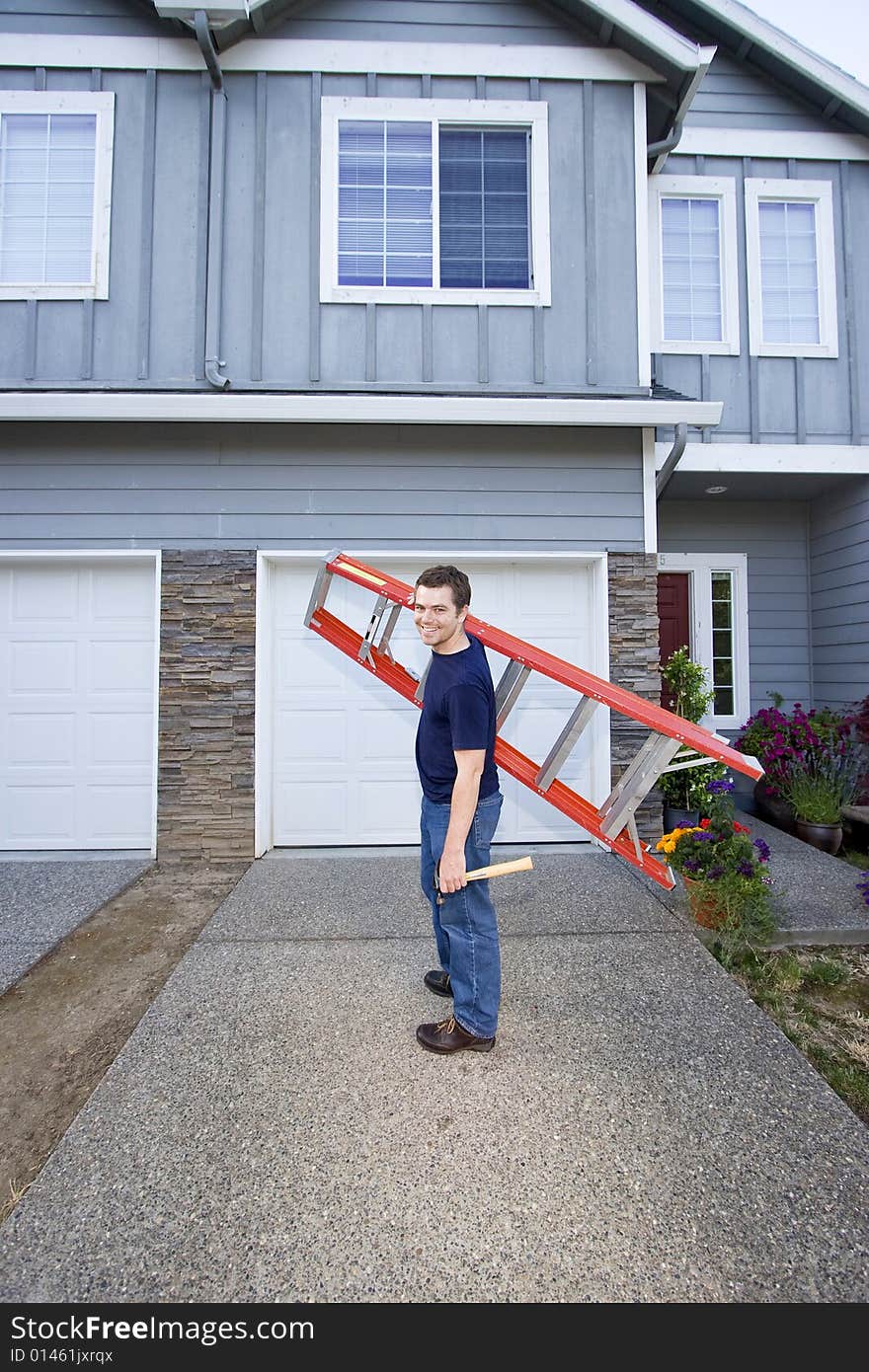 Smiling man standing in front of house holding ladder and hammer. Vertically framed photo. Smiling man standing in front of house holding ladder and hammer. Vertically framed photo.